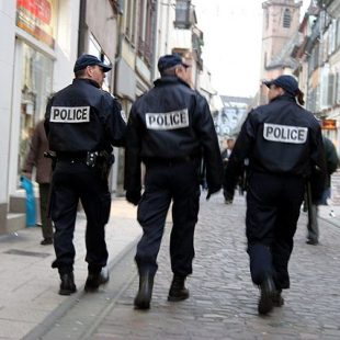 photographie de trois policiers patrouillant dans une rue, de dos