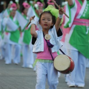 Photographie d'une fillette tapant sur un tambour dans un défilé