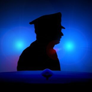 Silhouette d'un policier éclairée par une lumière bleue.