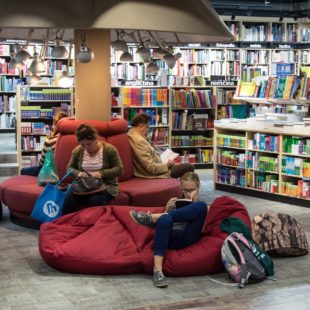 Intérieur d'une bibliothèque avec des usagers lisant dans des poufs