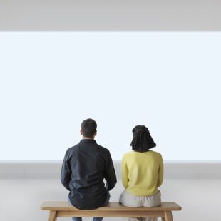 Couple assis dans un musée devant un écran lumineux blanc