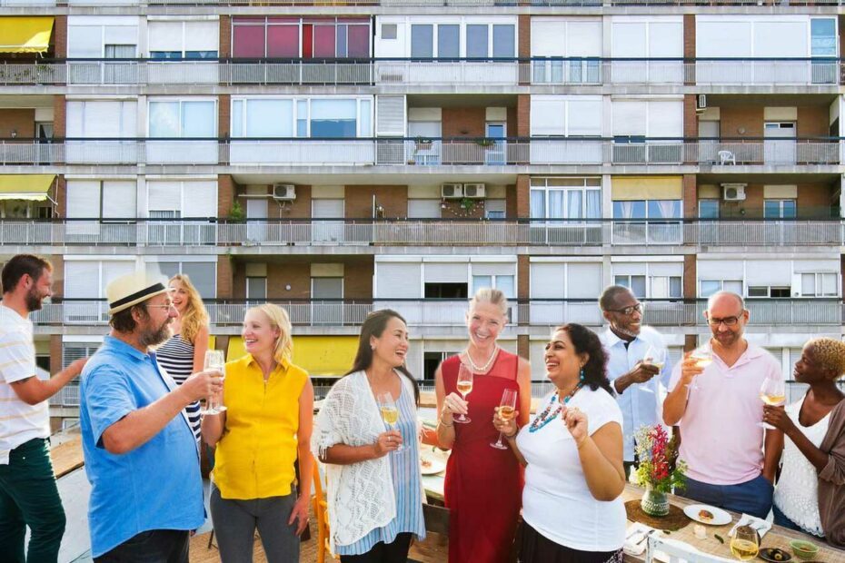 Un groupe de personnes prend l'apéritif sur une terrasse donnant sur un immeuble.