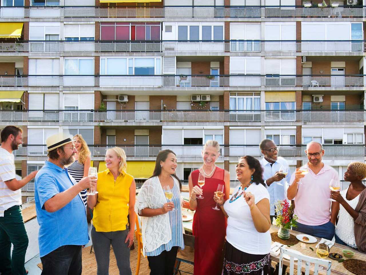 Un groupe de personnes prend l'apéritif sur une terrasse donnant sur un immeuble.