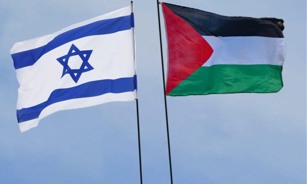 Drapeaux au vent d'Israel et de la Palestine dos à dos sur fond de ciel bleu