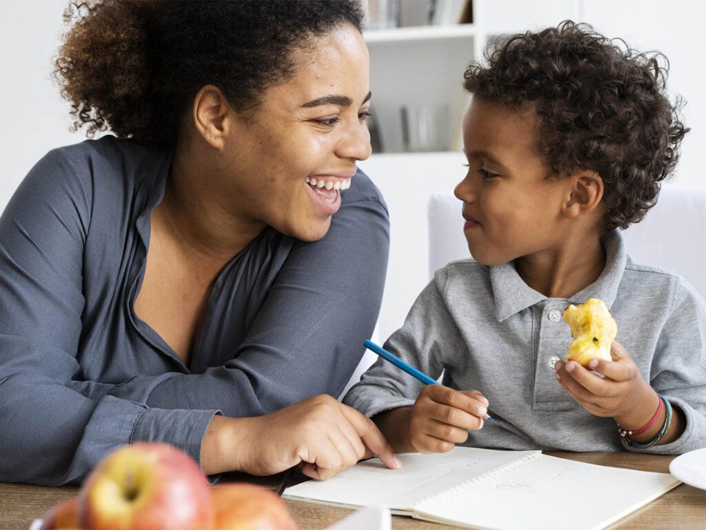 Partage de moment agréable entre une mère et son enfant autour du dessin. L'enfant mange une pomme