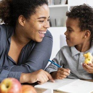 Partage de moment agréable entre une mère et son enfant autour du dessin. L'enfant mange une pomme