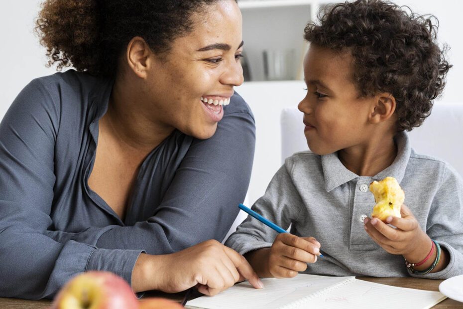 Partage de moment agréable entre une mère et son enfant autour du dessin. L'enfant mange une pomme