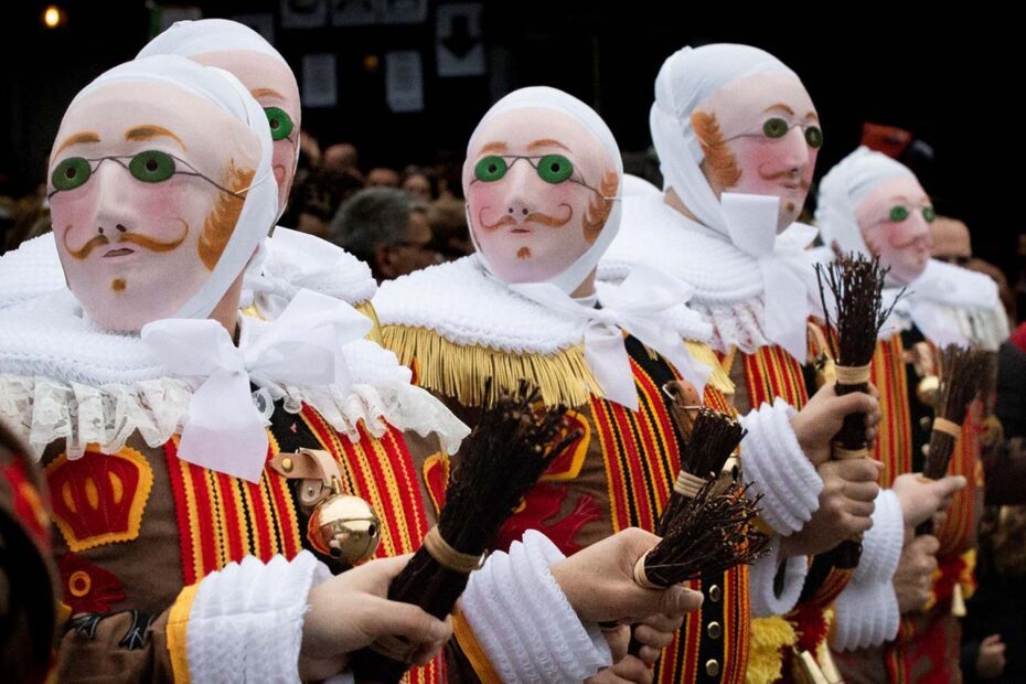 Photographie en couleurs de format paysage composée de 5 personnages costumés (rassemblement des Gilles) dans une foule. Les personnages au premier plan sont cadrés en plan poitrine. La photographie est très colorée.