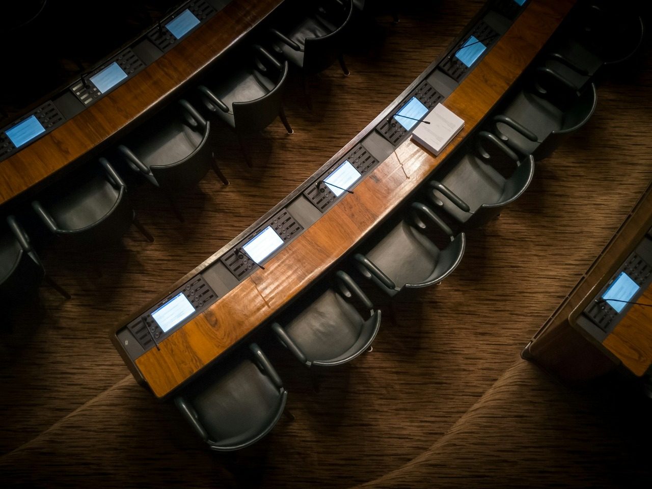 Photo illustrant les tables avec micro et siège des députés au Parlement.